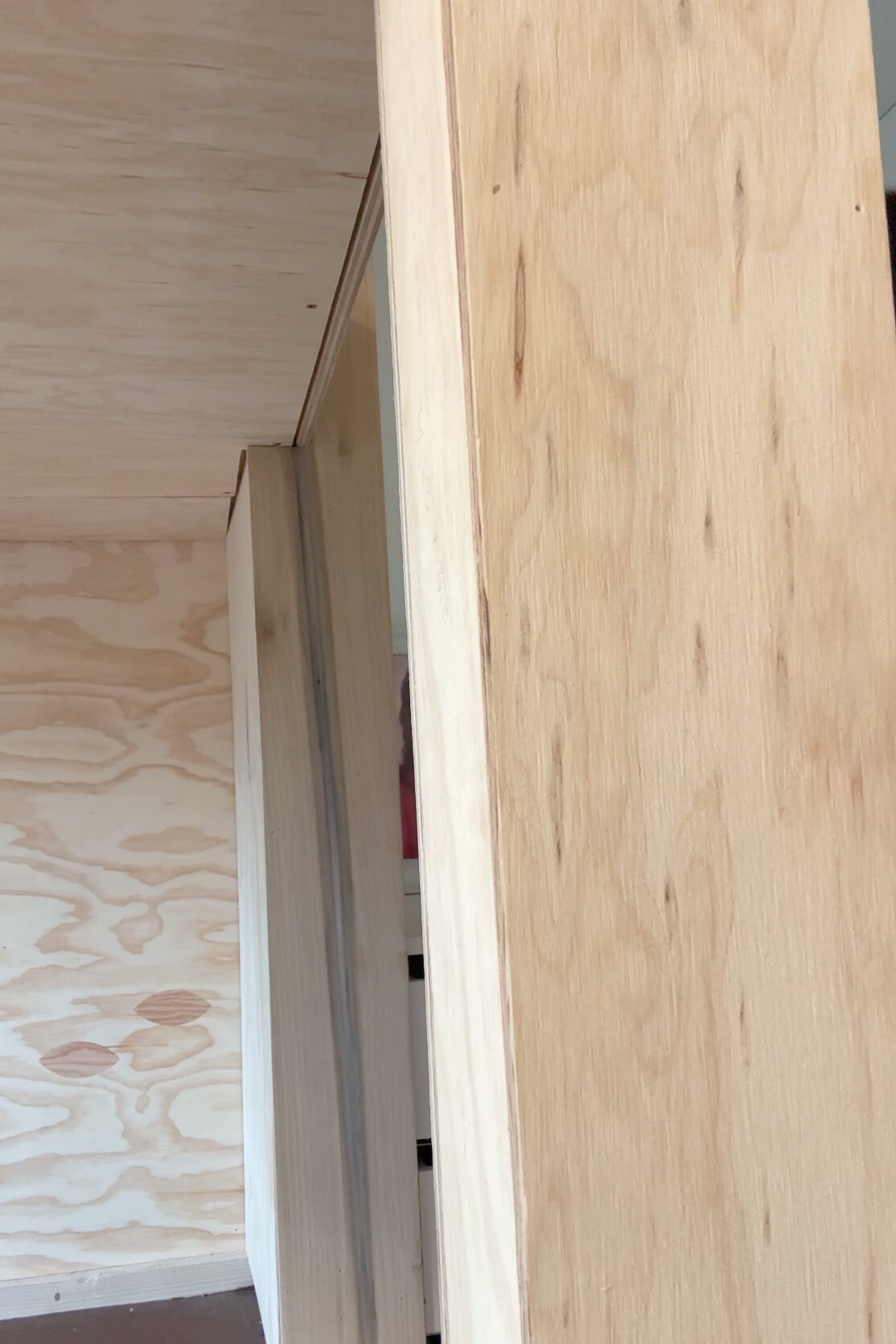 Using a router to clean up the uneven edges of plywood on a bunk bed frame.